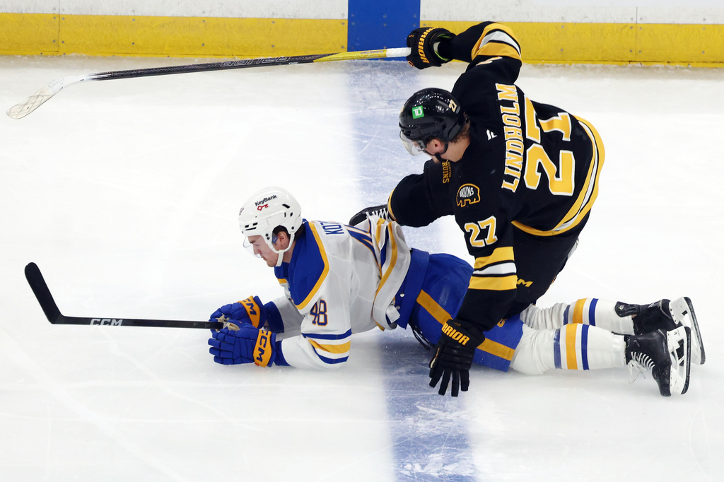 Boston Bruins' Hampus Lindholm (27) falls on Buffalo Sabres' Tyson Kozak (48) while battling for the puck during the first period in Game 4 of a first-round NHL hockey Stanley Cup playoff series, Sunday, April 26, 2026, in Boston. (AP Photo/Michael Dwyer)