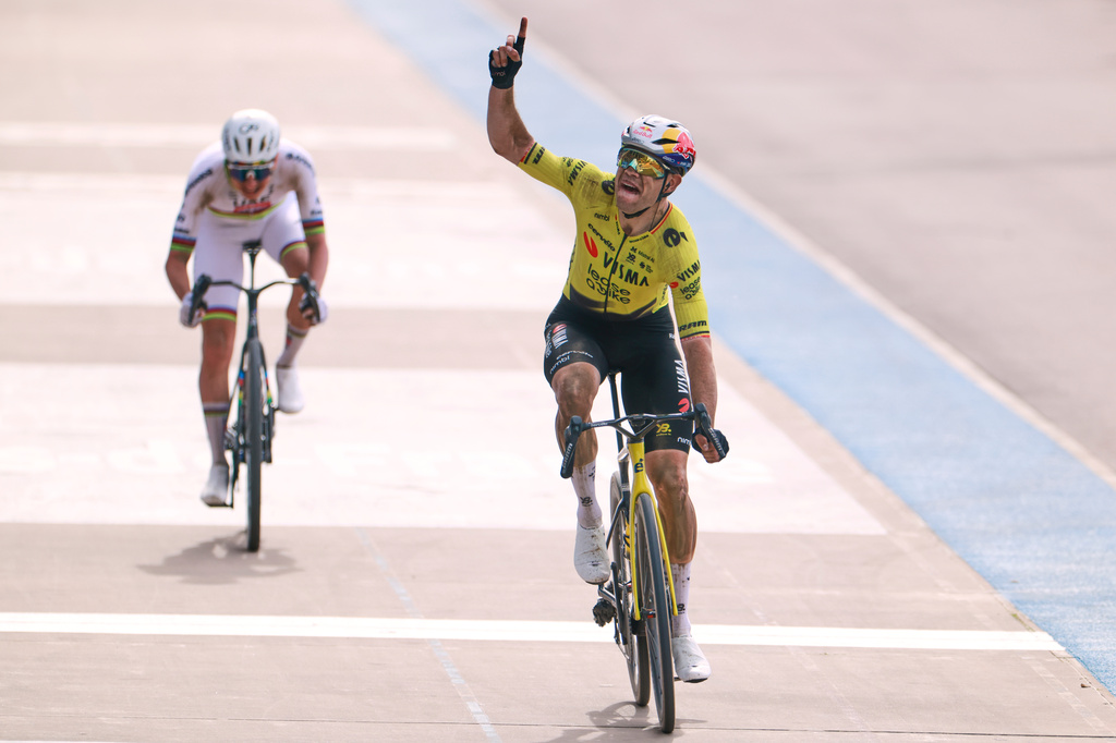 Belgium's Wout van Aert crosses the finish line ahead of Tadej Pogacar of Slovenia, left, to win the Paris-Roubaix cycling race in Roubaix, France, Sunday, April 12, 2026. Van Aert pointed his finger skywards to commemorate Belgian cyclist Michael Goolaerts who died after crashing in the race in 2018. (AP Photo/Jean-Francois Badias)