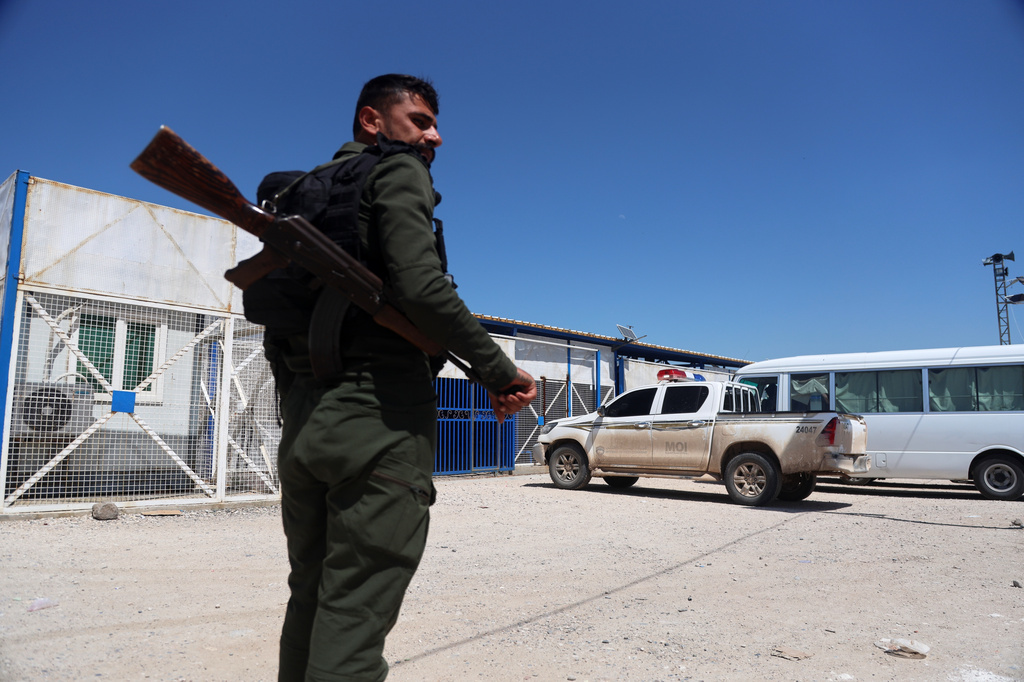 A soldier stands guard as vehicles arrive at Roj Camp in eastern Syria, housing people with alleged ties to Islamic State militants, to transport Australian families to Damascus as part of a second repatriation effort by Syrian authorities, Friday, April 24, 2026. (AP Photo/Baderkhan Ahmad)