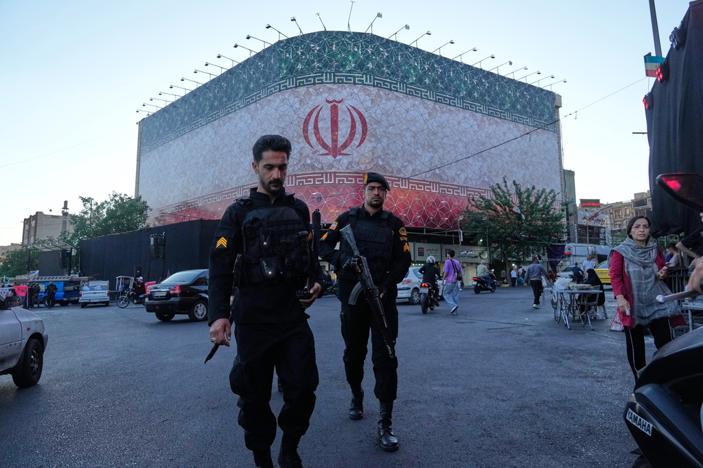 Policemen walk in front of a huge banner showing Iranian flag at the Islamic Revolution square in Tehran, Iran, Sunday, June 14, 2026. (AP Photo/Vahid Salemi)