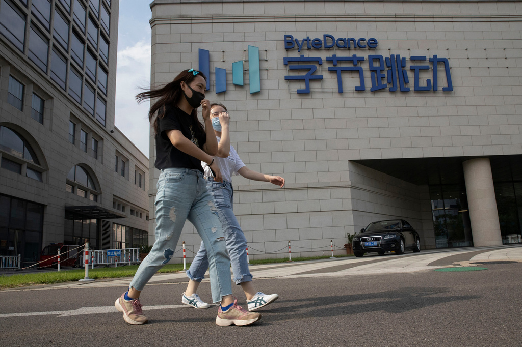 FILE - Women wearing masks to prevent the spread of the coronavirus chat as they pass by the headquarters of ByteDance, owners of TikTok, in Beijing on Aug. 7, 2020. (AP Photo/Ng Han Guan, File)