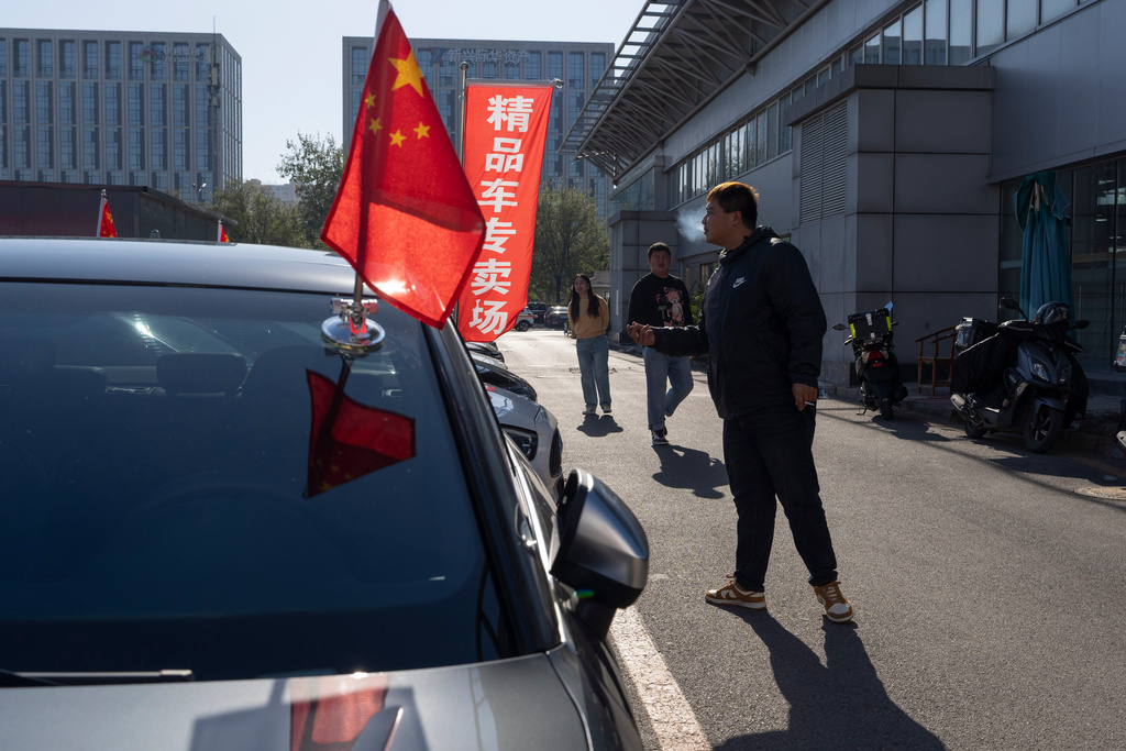 A man stands near second hand luxury cars for sale in Beijing on Friday, Nov. 21, 2025. (AP Photo/Ng Han Guan)