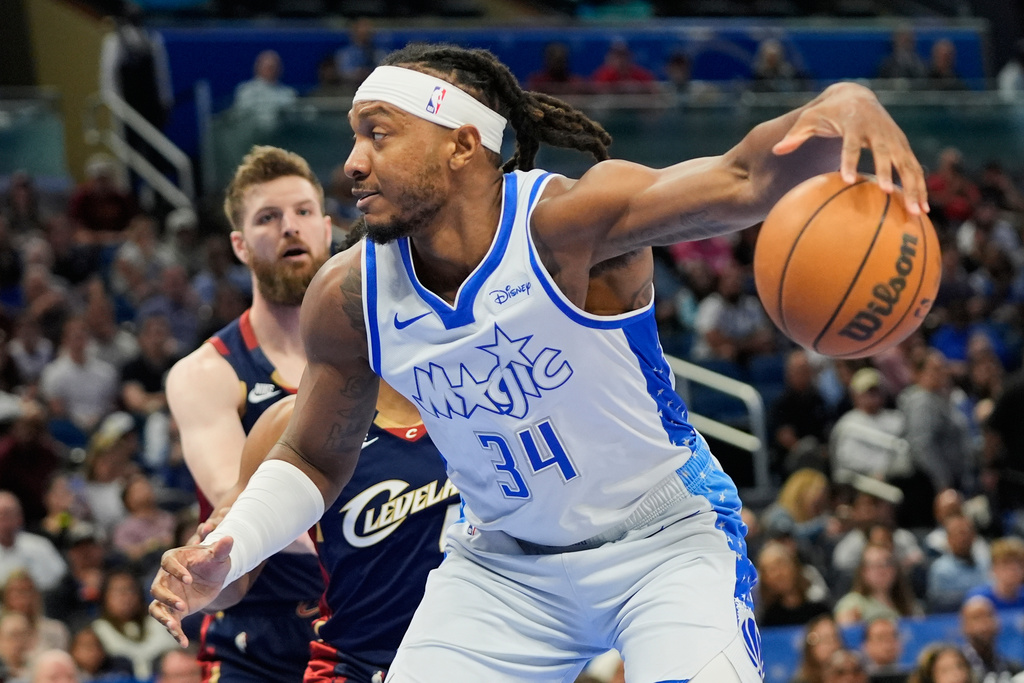 Orlando Magic center Wendell Carter Jr. (34) moves to the basket against Cleveland Cavaliers guard Donovan Mitchell and forward Dean Wade during the first half of an NBA basketball game, Wednesday, March 11, 2026, in Orlando, Fla. (AP Photo/John Raoux)