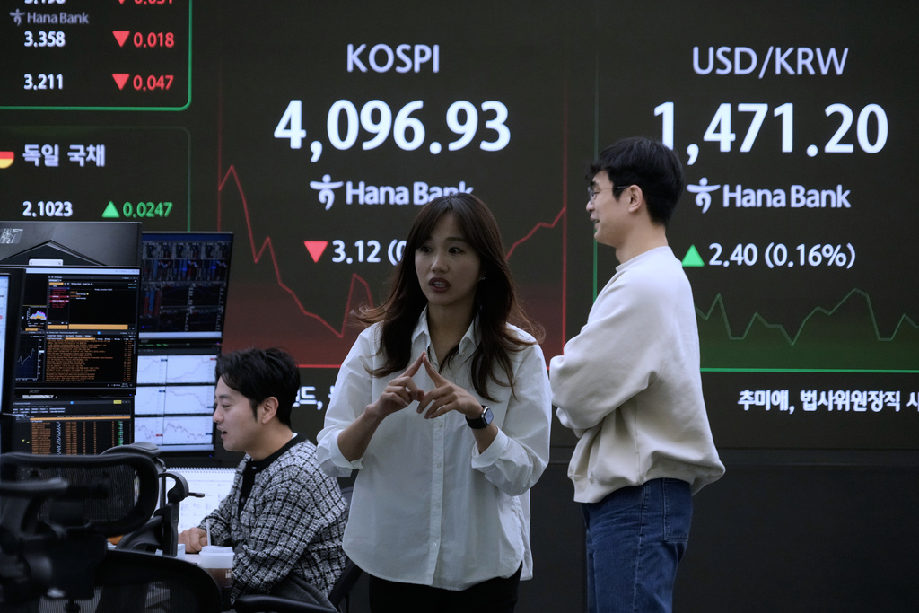 Currency traders work near a screen showing the Korea Composite Stock Price Index (KOSPI) and the foreign exchange rate between U.S. dollar and South Korean won, top right, at the foreign exchange dealing room of the Hana Bank headquarters in Seoul, South Korea, Monday, Dec. 8, 2025. (AP Photo/Ahn Young-joon)