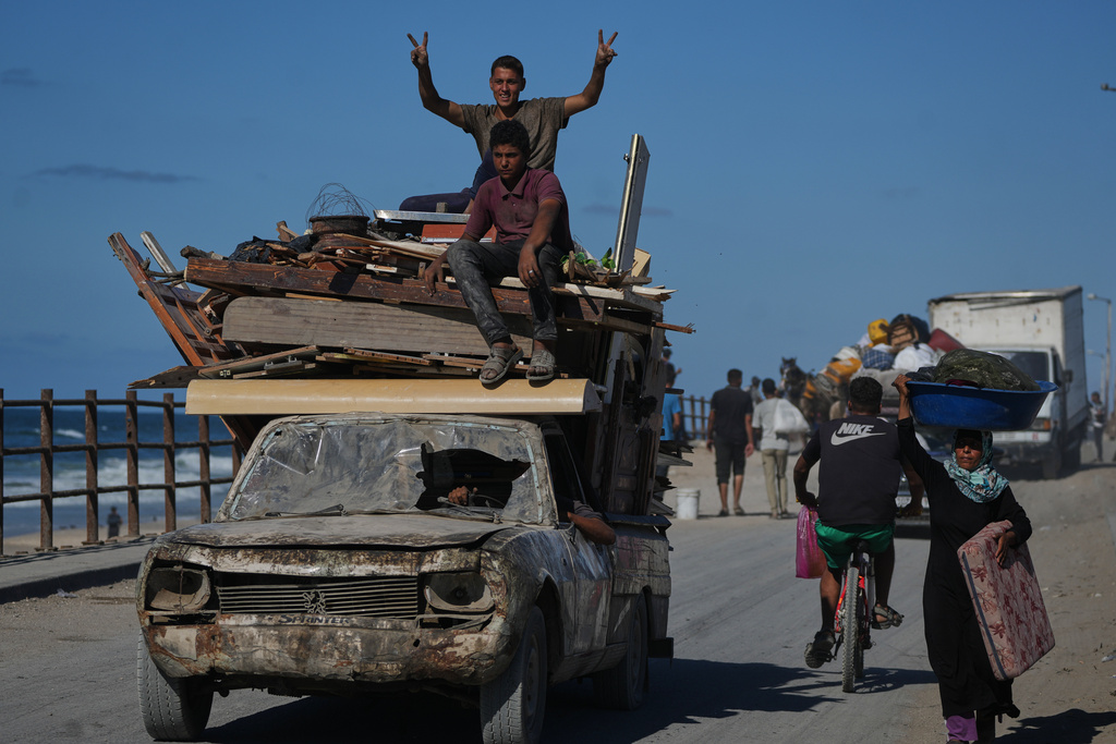 A displaced Palestinian flashes a V-sign to the camera while fleeing northern Gaza along the coastal road near Wadi Gaza, Wednesday, Oct, 1, 2025. (AP Photo/Abdel Kareem Hana)