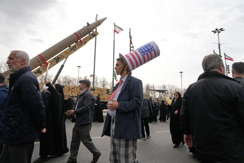 A man wears a Uncle Sam's hat as he stands in front of an Iranian-built missile during an annual rally marking 1979 Islamic Revolution at the Azadi (Freedom) sq. in Tehran, Iran, Wednesday, Feb. 11, 2026. (AP Photo/Vahid Salemi)
