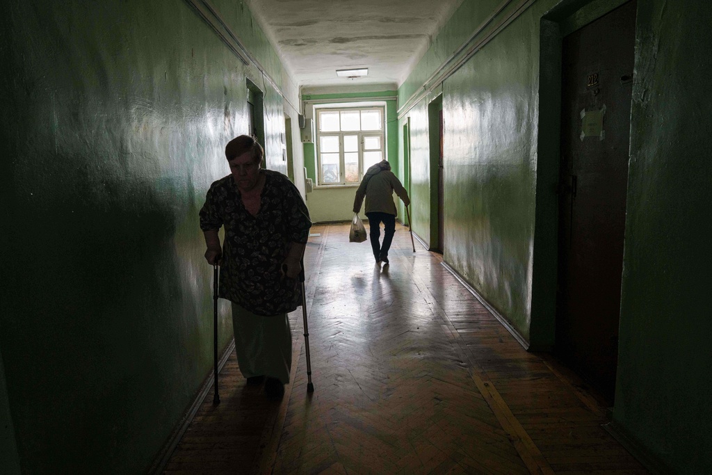 Elderly women walk in a corridor at a hostel for the displaced in Dnipro, Ukraine, Wednesday, Oct. 8, 2025. (AP Photo/Evgeniy Maloletka)
