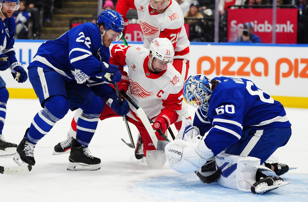 Toronto Maple Leafs goaltender Joseph Woll (60) makes a save as Jake McCabe (22) defends against Detroit Red Wings' Dylan Larkin (71) and James van Riemsdyk (21) during the first period of an NHL hockey game in Toronto, Wednesday, Jan. 21, 2026. (Frank Gunn/The Canadian Press via AP)