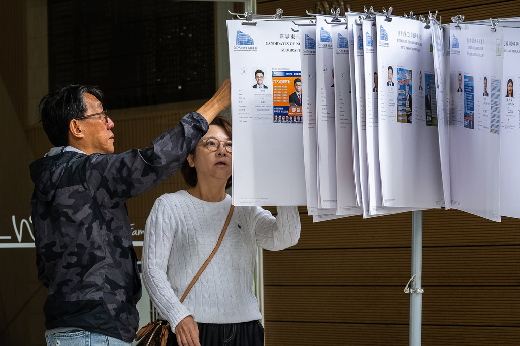 People read the candidates information at a polling station near the site of the fire at Wang Fuk Court in the Tai Po district during the Legislative Council General Election in Hong Kong on Sunday, Dec. 7, 2025. (AP Photo/Chan Long Hei)