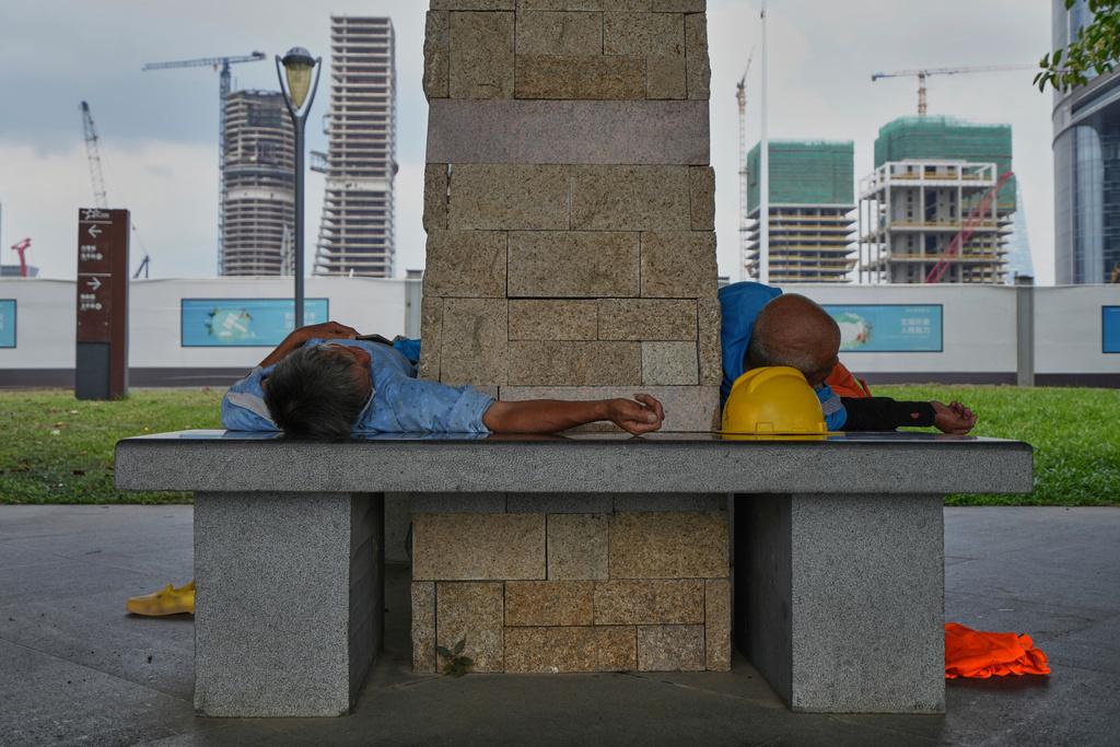 Workers take nap on a bench of a public park during a lunch break hour near a construction site, at the Shenzhen Bay, in Shenzhen, China's Guangdong province, Wednesday, Sept. 17, 2025. (AP Photo/Andy Wong)