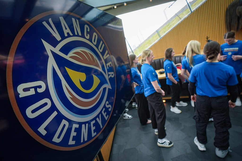 FILE - Vancouver Goldeneyes players stand near a display showing their new logo and team name following an unveiling at a PWHL hockey news conference, Nov. 6, 2025, in Vancouver, British Columbia. (Darryl Dyck/The Canadian Press via AP, File)