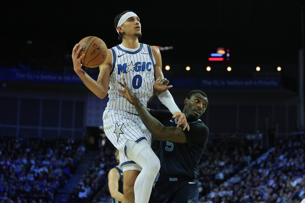 Orlando Magic guard Anthony Black (0) collides with Memphis Grizzlies guard Vince Williams Jr. (5) during the first half of NBA basketball game Sunday, Jan. 18, 2026, in London. (AP Photo/Kin Cheung)