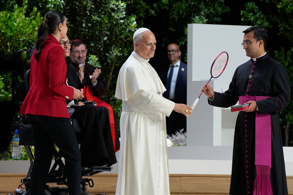 Pope Leo XIV holds a Badminton racket presented to him by Rio 2016 Olympic champion Carolina Marin and by Paralympic athlete Teresa Perales, second from right, during the meeting "Building networks with the world of culture, art, economy and sport" at the Movistar Arena in Madrid, Spain, Sunday, June 7, 2026 (AP Photo/Alessandra Tarantino)
