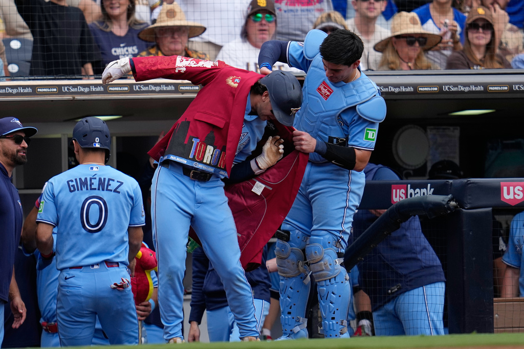 Toronto Blue Jays' Ernie Clement, center, gets a jacket from catcher Brandon Valenzuela after hitting a two-run home run during the fourth inning of a baseball game against the San Diego Padres Sunday, July 12, 2026, in San Diego. (AP Photo/Gregory Bull)