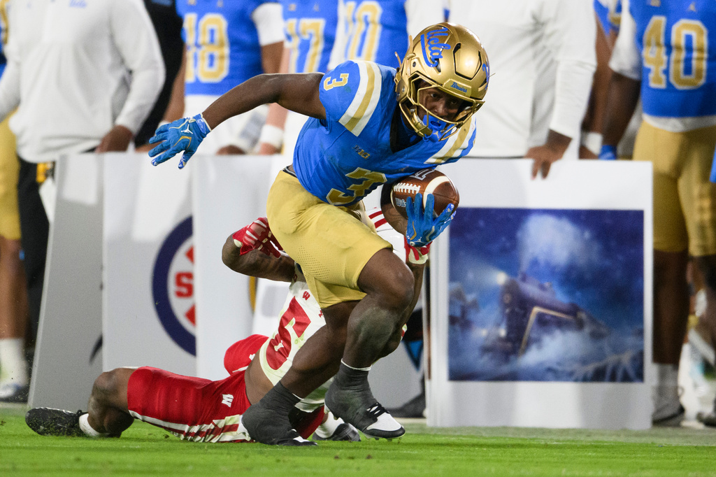 UCLA running back Wayne Knight (3) runs with the ball past Wisconsin cornerback Bryce West (5) during the second half of an NCAA college football game Saturday, Oct. 17, 2026, in Pasadena, Calif. (AP Photo/Kyusung Gong)