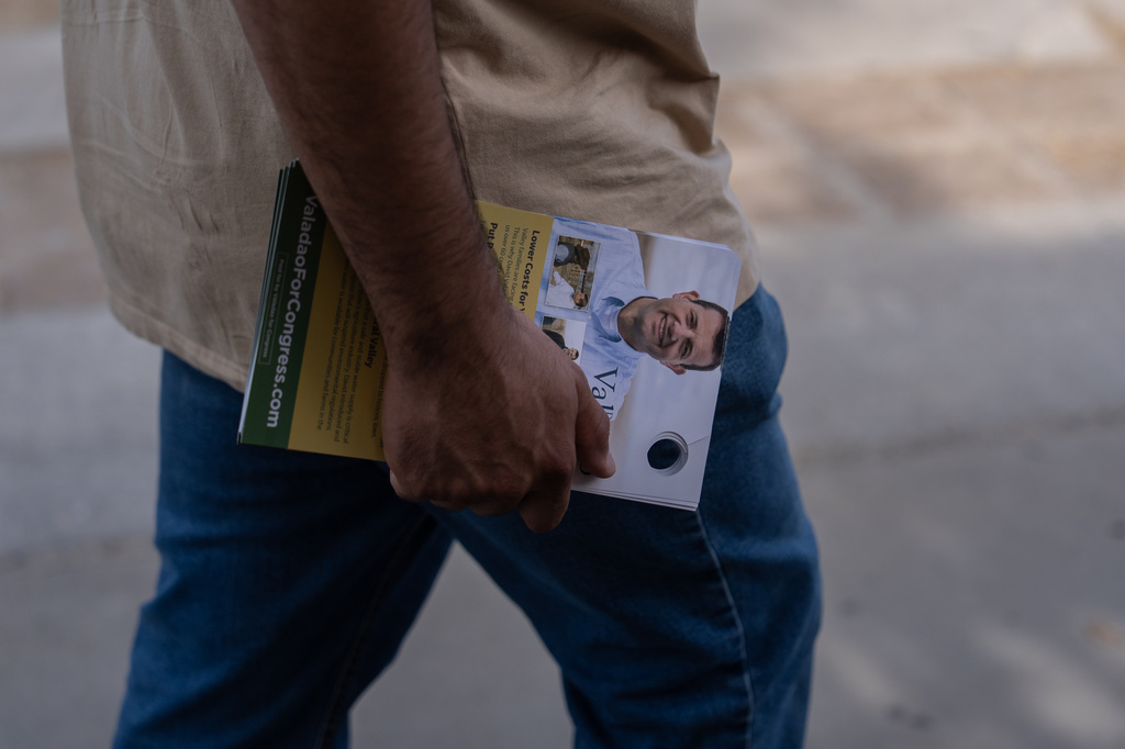Volunteer Jesus Hernandez carries campaign door hangers while canvassing for U.S. Rep. David Valadao, R-Calif., in Hanford, Calif., Friday, Aug. 21, 2026. (AP Photo/Jae C. Hong)