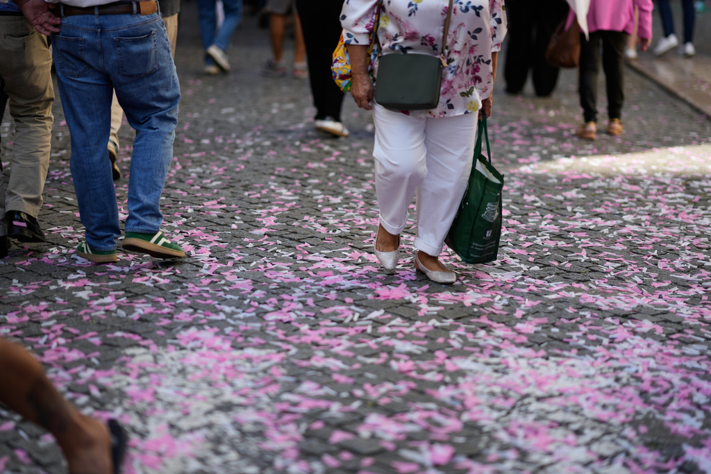 People walk on confetti left behind by supporters of the left-of-center coalition Viver Lisboa, (To Live Lisbon), campaigning in downtown Lisbon ahead of Sunday's municipal elections, Friday, Oct. 10, 2025. (AP Photo/Armando Franca)