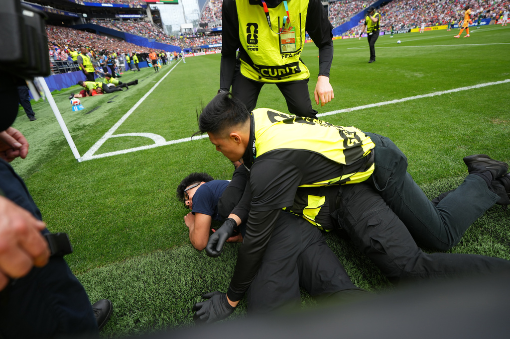 A pitch invader is held by security during the World Cup round of 32 soccer match between Belgium and Senegal in Seattle, Wednesday, July 1, 2026. (AP Photo/Lindsey Wasson)