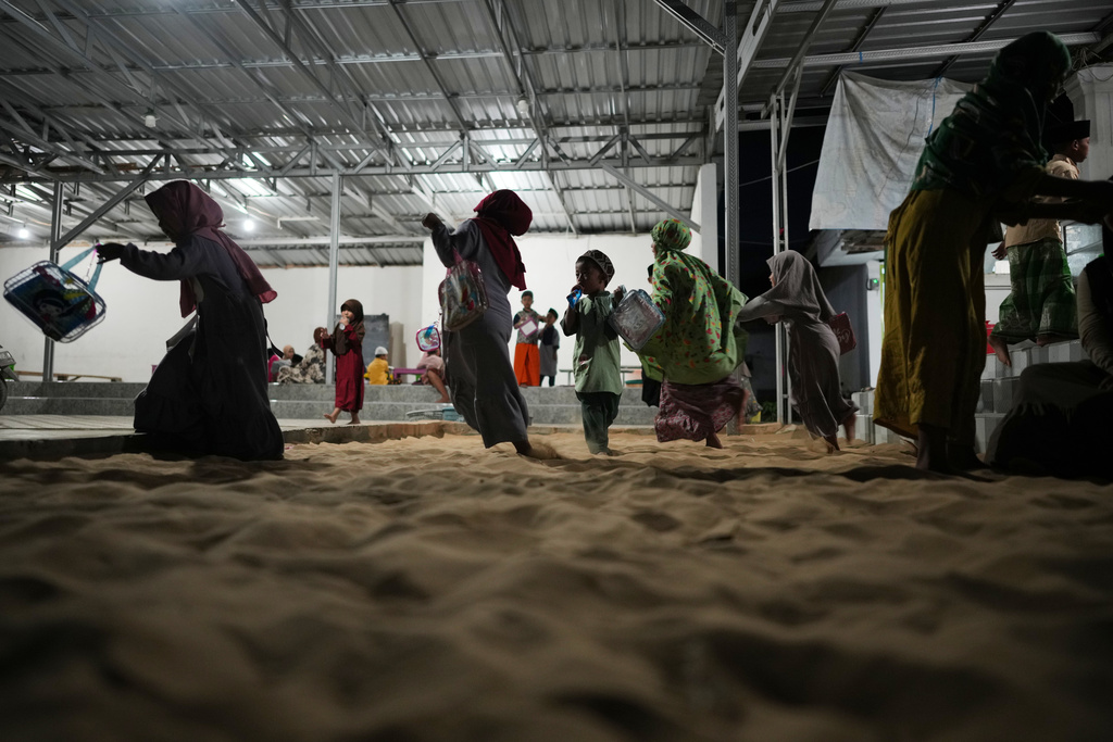 Children play in a sandpit after an evening Quran class in Legung Timur village in Sumenep on Madura Island, Indonesia, Tuesday, Sept. 9, 2025. (AP Photo/Dita Alangkara)