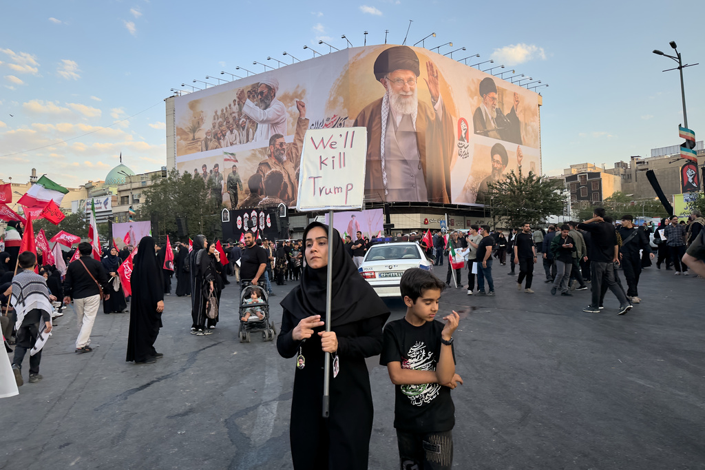 A woman holds a sign reading "We'll Kill Trump" while waiting in Islamic Revolution Square for the funeral procession of the slain Iranian Supreme Leader Ayatollah Ali Khamenei beneath a billboard depicting Khamenei in Tehran, Iran, Monday, July 6, 2026. (AP Photo/Altaf Qadri)