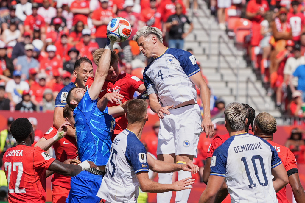 Canada goalkeeper Maxime Crepeau punches the ball clear as Bosnia's Tarik Muharemovic attempts to head the ball during the World Cup Group B soccer match between Canada and Bosnia in Toronto, Friday, June 12, 2026. (AP Photo/Stephanie Scarbrough)