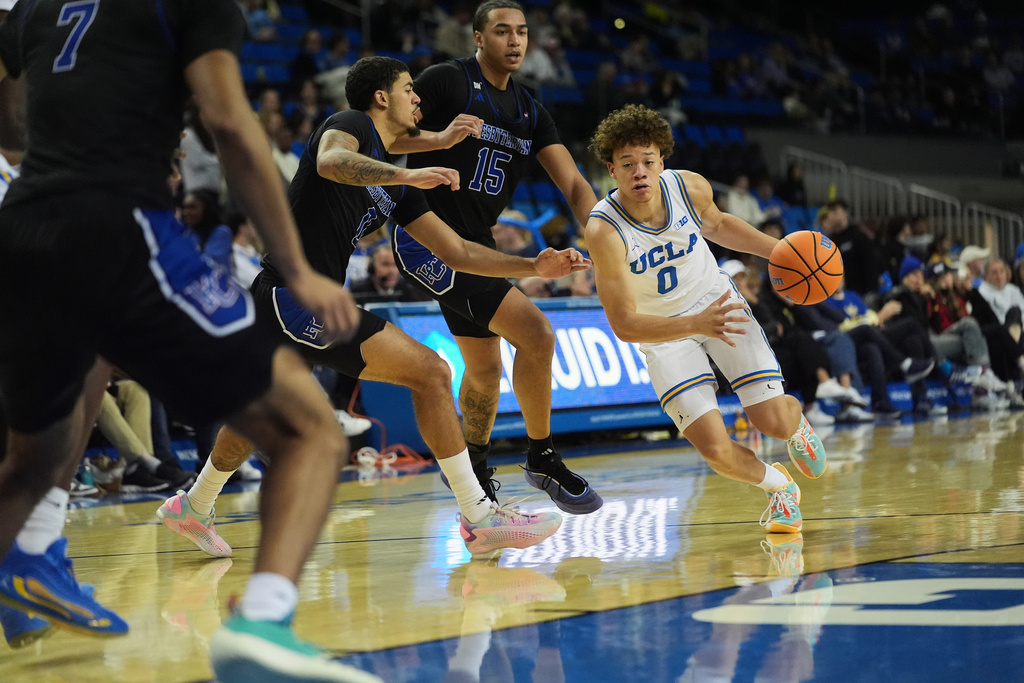 UCLA guard Trent Perry (0) moves around Presbyterian forward Jonah Pierce (15) to score a point during the first half of an NCAA college basketball game in Los Angeles, Friday, Nov. 21, 2025. (AP Photo/Damian Dovarganes)