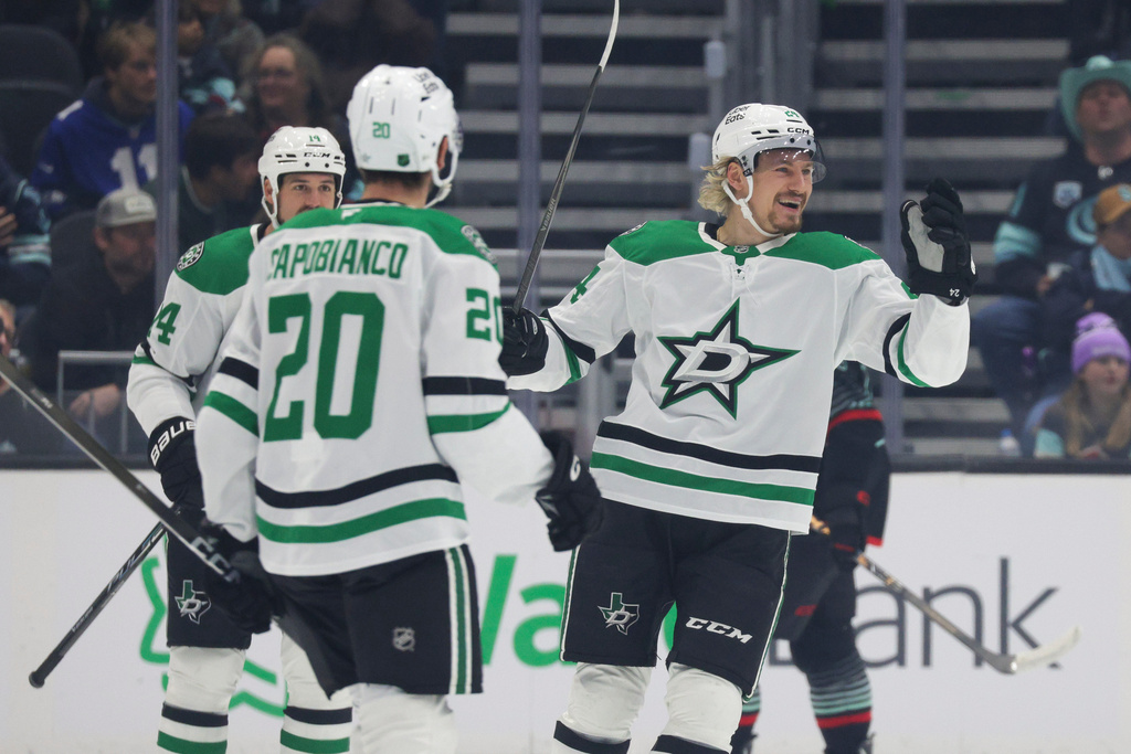 Dallas Stars center Roope Hintz, right, celebrates with defenseman Kyle Capobianco (20) and left wing Jamie Benn (14) after scoring during the first period of an NHL hockey game against the Seattle Kraken Wednesday, Nov. 26, 2025, in Seattle. (AP Photo/Jason Redmond)