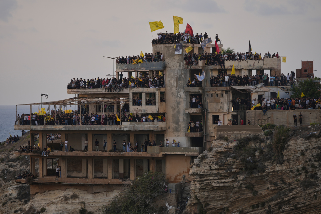 Hezbollah supporters stand on building to watch the landmark Raouche sea rock which illuminated by a portrait of late Hezbollah leader Sayyed Hassan Nasrallah during an event commemorating his anniversary assassination, in Beirut, Lebanon, Thursday, Sept. 25, 2025. (AP Photo/Hussein Malla)