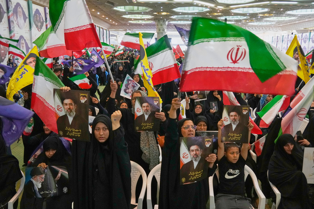 Government supporters hold Iranian flags and pictures of Iran's Supreme Leader, Ayatollah Mojtaba Khamenei, during a ceremony honoring the armed forces and those killed in the war with Israel and the U.S. at the Imam Khomeini Grand Mosque in Tehran, Iran, Sunday, May 24, 2026. (AP Photo/Vahid Salemi)