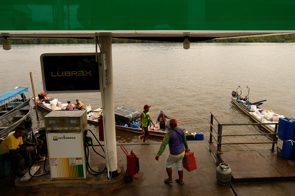 Boatmen operating Catraia, a traditional boat used on the Oiapoque River, prepare for the crossing with a load of gasoline canisters filled at a Petrobras gas station in a port in the city of Oiapoque, Amapa state, Brazil, Tuesday, March 10, 2026. (AP Photo/Eraldo Peres)