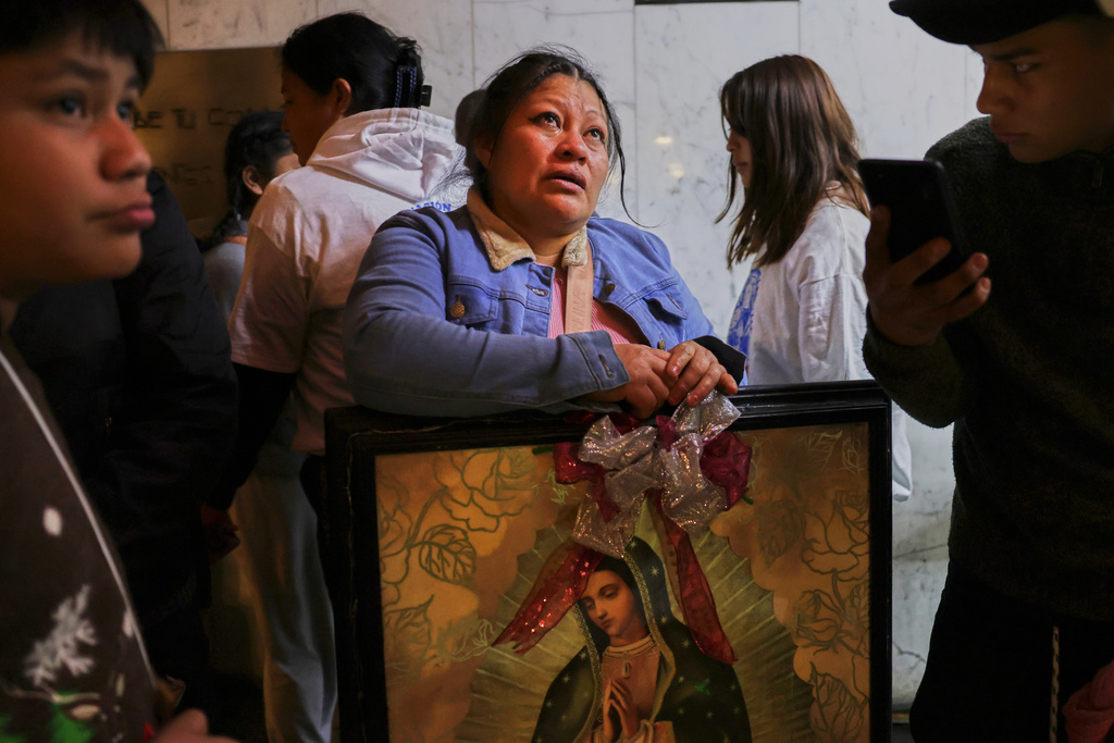A woman cries as she looks up at the Virgin of Guadalupe image handing on the wall at the Basilica of Our Lady of Guadalupe in Mexico City, on her feast day, Friday, Dec. 12, 2025. (AP Photo/Claudia Rosel)