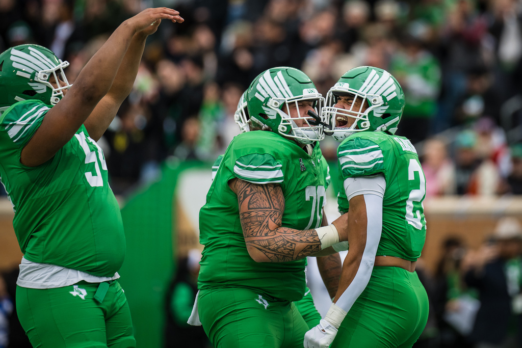 North Texas offensive lineman Tay Yanta II, center, and running back Caleb Hawkins, right, celebrate after a touchdown during an NCAA college football game against Temple, Friday, Nov. 28, 2025, Denton, Texas. (AP Photo/Jessica Tobias)
