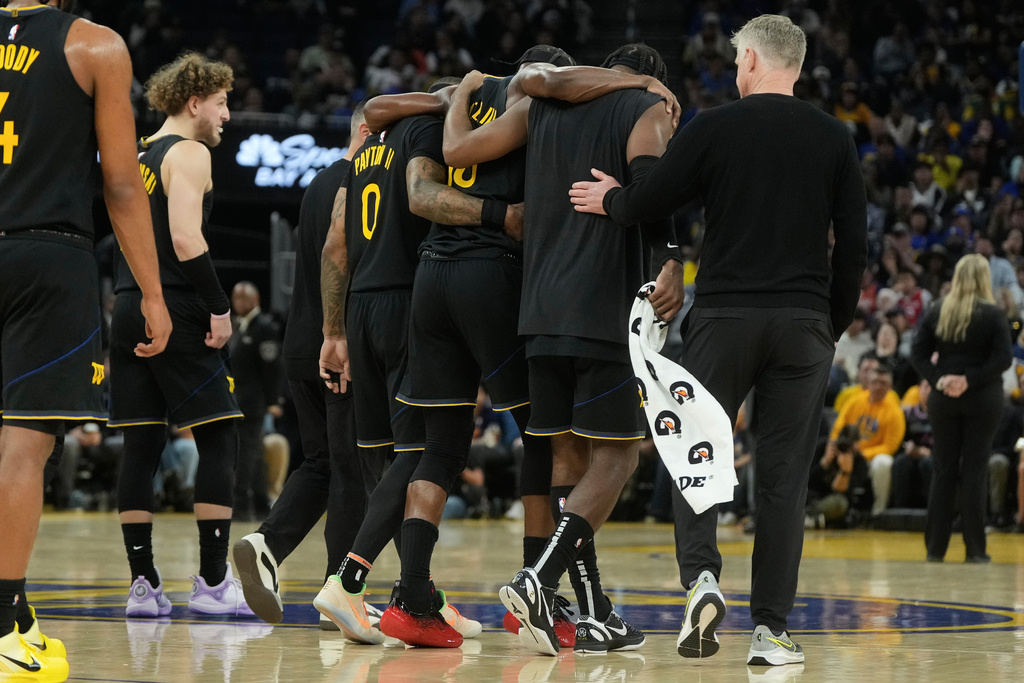 Golden State Warriors forward Jimmy Butler III, middle, is helped off the floor by teammates during the second half of an NBA basketball game against the Miami Heat in San Francisco, Monday, Jan. 19, 2026. (AP Photo/Jeff Chiu)