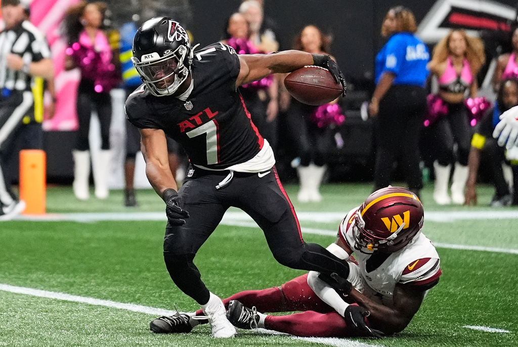 Atlanta Falcons running back Bijan Robinson (7) scores a touchdown past Washington Commanders cornerback Mike Sainristil, right, during the first half of an NFL football game, Sunday, Sept. 28, 2025, in Atlanta. (AP Photo/Brynn Anderson)