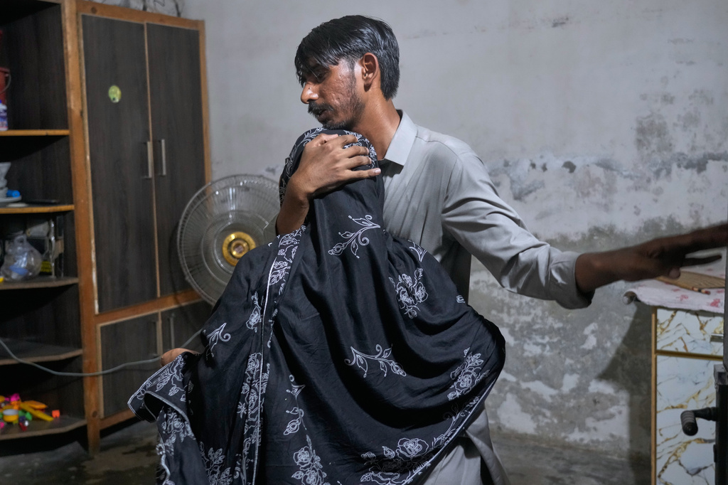 A man comforts a woman mourning over the death of her child, killed after the roof of a tutoring center under-construction collapsed, on the outskirts of Lahore, Pakistan, Tuesday, June 30, 2026. (AP Photo/K.M Chaudary)