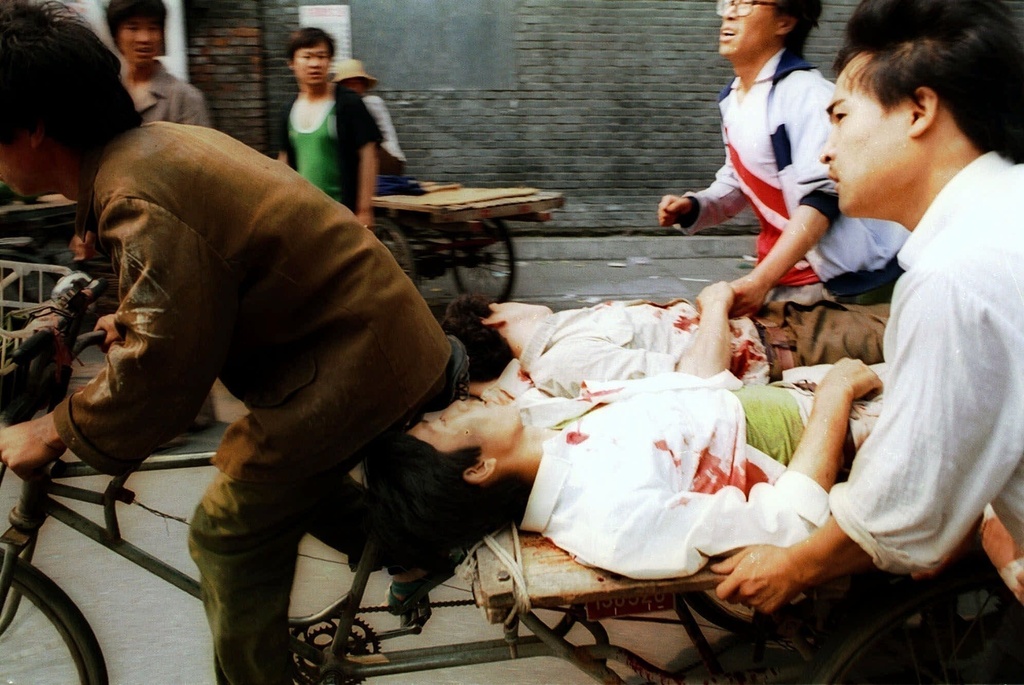 FILE - A rickshaw driver transports wounded people, with the help of bystanders, to a nearby hospital in Beijing, on Sunday, June 4, 1989, after PLA soldiers fired rounds towards crowds gathered outside Tiananmen Square. (AP Photo/Liu Heung Shing, File)