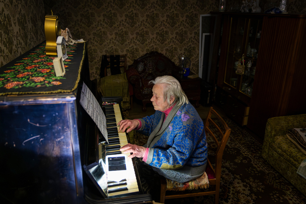 Raisa Derhachova plays the piano during a power outage caused by Russia's regular air strikes on the country's energy facilities in Kyiv, Ukraine, Tuesday, Jan. 13, 2026. (AP Photo/Dan Bashakov)