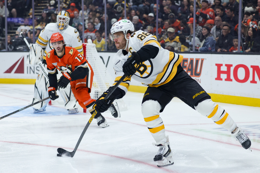 Boston Bruins right wing David Pastrnak, right, moves the puck ahead of Anaheim Ducks center Nikita Nesterenko (13) during the second period of an NHL hockey game Friday, Oct. 16, 2026, in Anaheim, Calif. (AP Photo/Ryan Sun)
