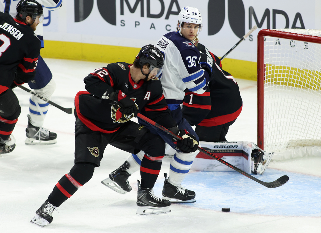 Ottawa Senators' Thomas Chabot, center, and Winnipeg Jets' Morgan Barron (36) battle for the puck during the first period of an NHL hockey game in Ottawa, Ontario, Saturday, Jan. 3, 2026. (Patrick Doyle/The Canadian Press via AP)