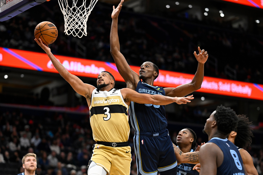 Washington Wizards guard CJ McCollum (3) scores a basket against Memphis Grizzlies center Christian Koloko during the first half of an NBA basketball game, Sunday, Dec. 28, 2025, in Washington. (AP Photo/John McDonnell)