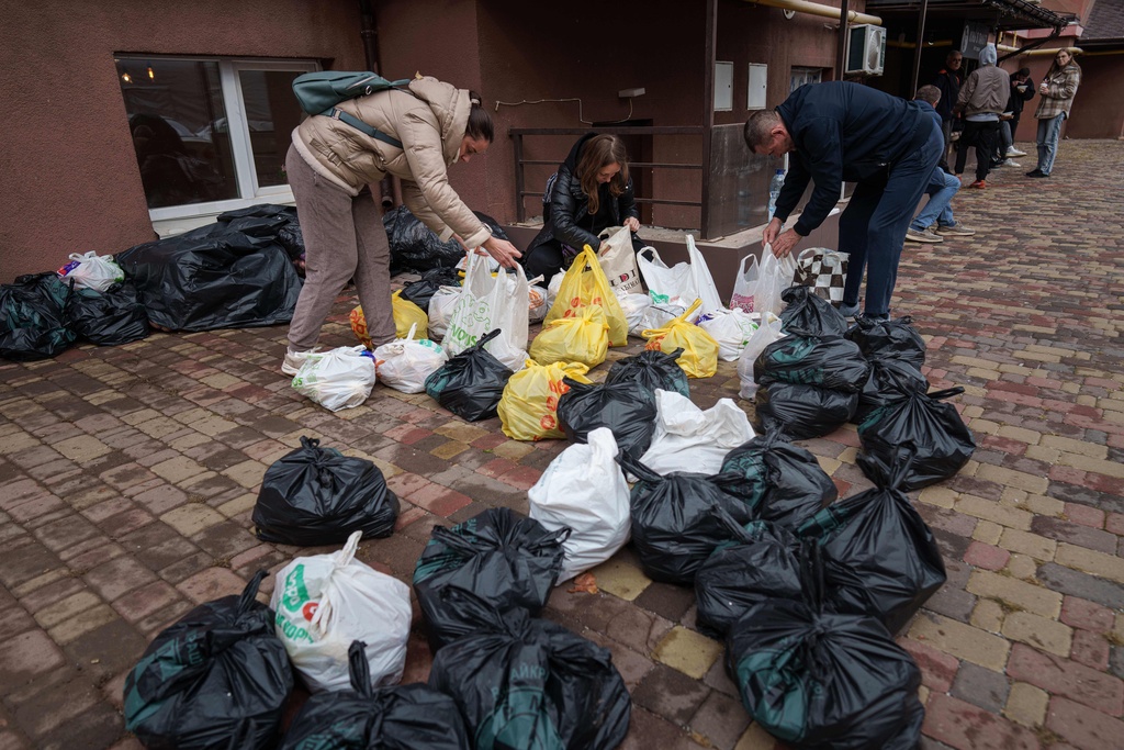 Local residents collect humanitarian aid after a Russian strike on residential neighborhood in Kyiv, Ukraine, on Monday, Sept. 29, 2025. (AP Photo/Evgeniy Maloletka)