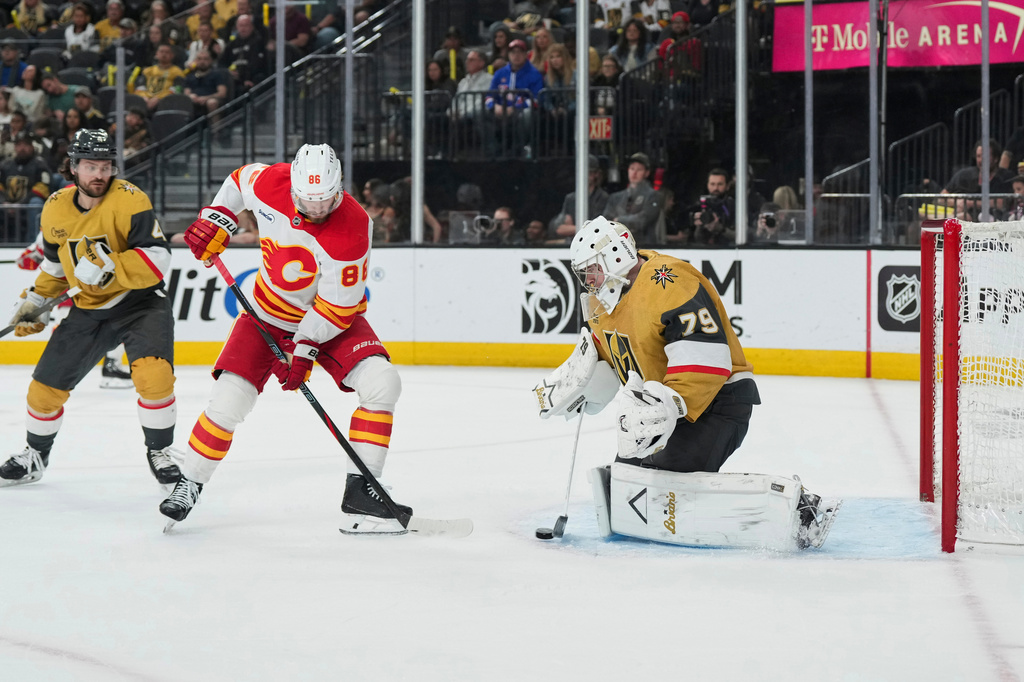 Vegas Golden Knights goaltender Carter Hart (79) stops a shot behind Calgary Flames left wing Joel Farabee (86) during the first period of an NHL hockey game Thursday, April 2, 2026, in Las Vegas. (AP Photo/Candice Ward)