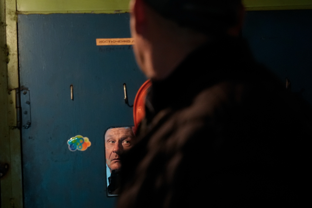 Oleksandr Leheda is reflected in a locker room mirror following his shift at the Chernihiv Oblenergo base, where due to continuous air alarms, Leheda's brigade was unable to fix power lines damaged following a Russian attack, Friday, Oct. 17, 2025, in Chernihiv, Ukraine. (AP Photo/Julia Demaree Nikhinson)