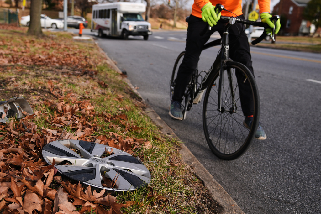Cyclist Barnaby Wickham steps down and dismounts his bike after spotting a lost hubcap on the side of the road, Thursday, Dec. 11, 2025, in Baltimore. (AP Photo/Stephanie Scarbrough)