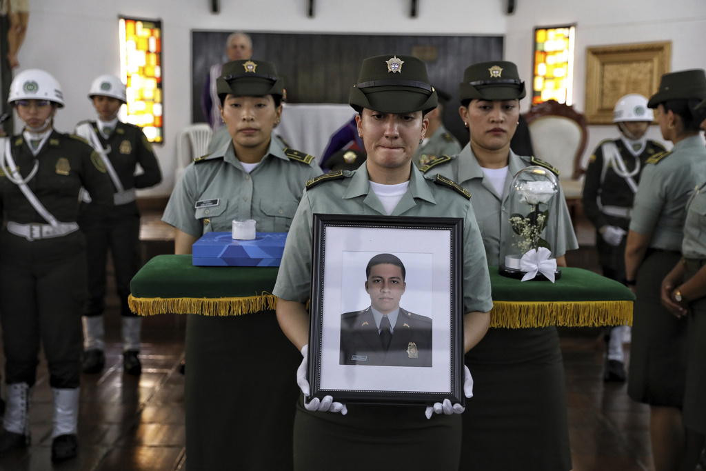 A police officer hold a portrait of Michael Astaiza, killed when a police helicopter was shot down by a dissident faction of the former FARC guerrilla group, during his funeral in Cali, Colombia, Monday, Aug. 25, 2025. (AP Photo/Santiago Saldarriaga)
