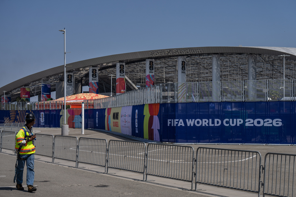 A worker walks past temporary fencing with FIFA World Cup 2026 signage outside SoFi Stadium, Friday, June 5, 2026, in Inglewood, Calif. (AP Photo/Jae C. Hong)