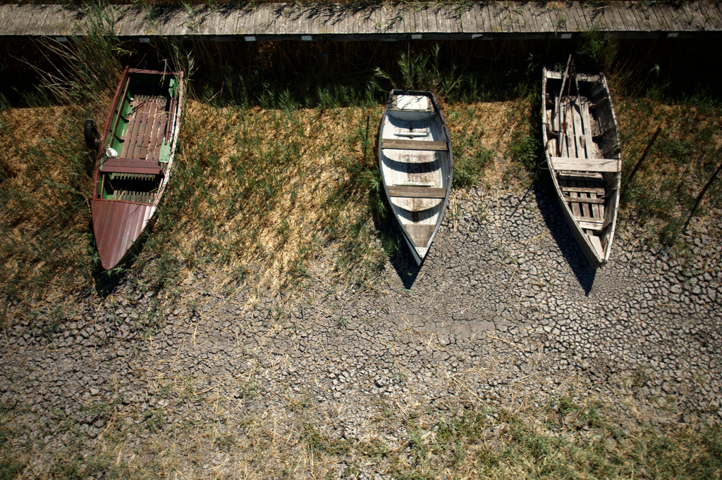 Boats lie on cracked soil at a dried-out marina on Lake Velence, Hungary, on Aug. 13. 2026. (AP Photo/Bela Szandelszky)