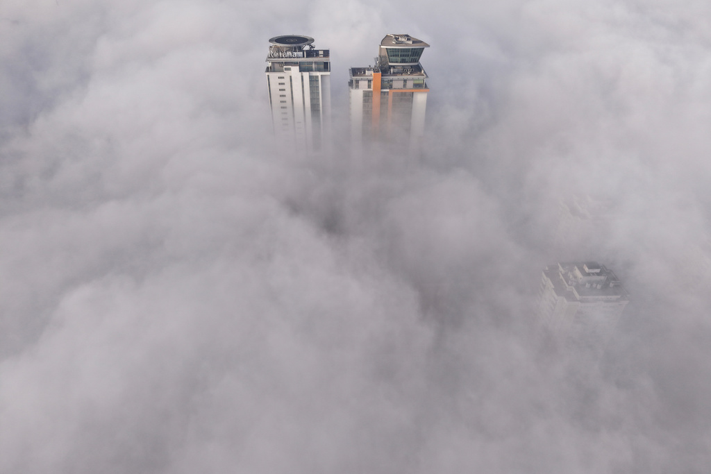 An aerial view of buildings peaking through a dense layer of fog in Sarajevo, Bosnia, Thursday, Dec. 18, 2025. (AP Photo/Armin Durgut)