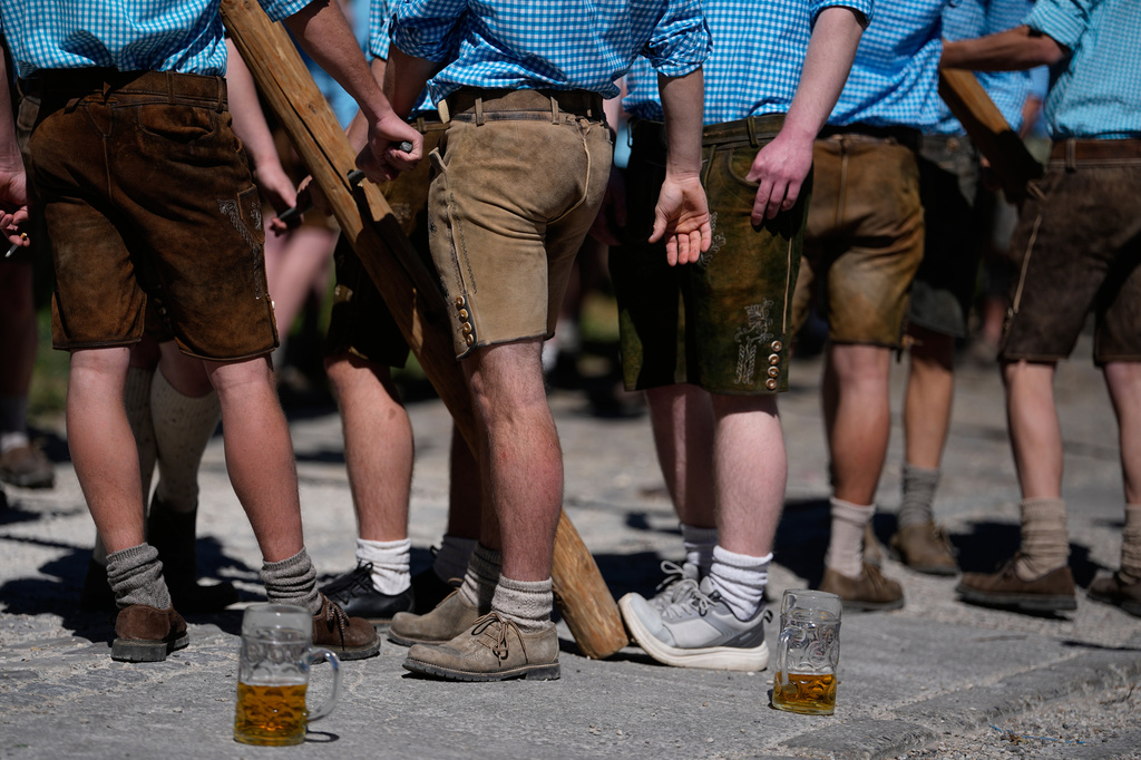 Young men wear leather trousers as they erect a traditional May pole in Kuehbach, Germany, Friday, May 1, 2026. (AP Photo/Matthias Schrader)