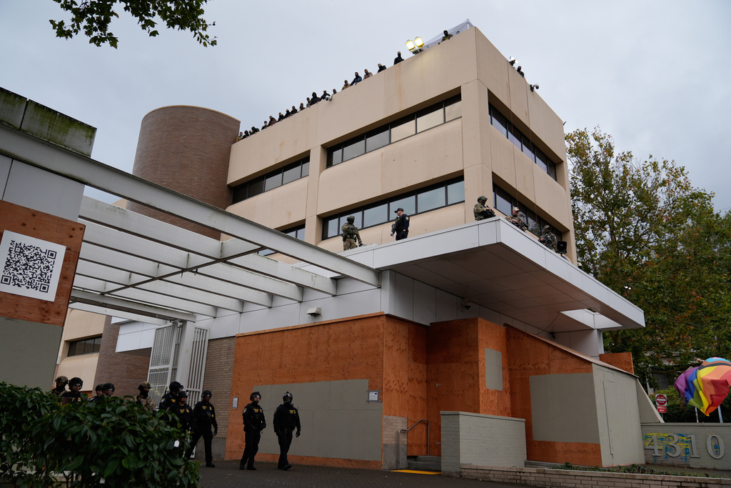 FILE - Law enforcement officers guard a U.S. Immigration and Customs Enforcement facility during a protest on Oct. 11, 2025, in Portland, Ore. (AP Photo/Jenny Kane, File)